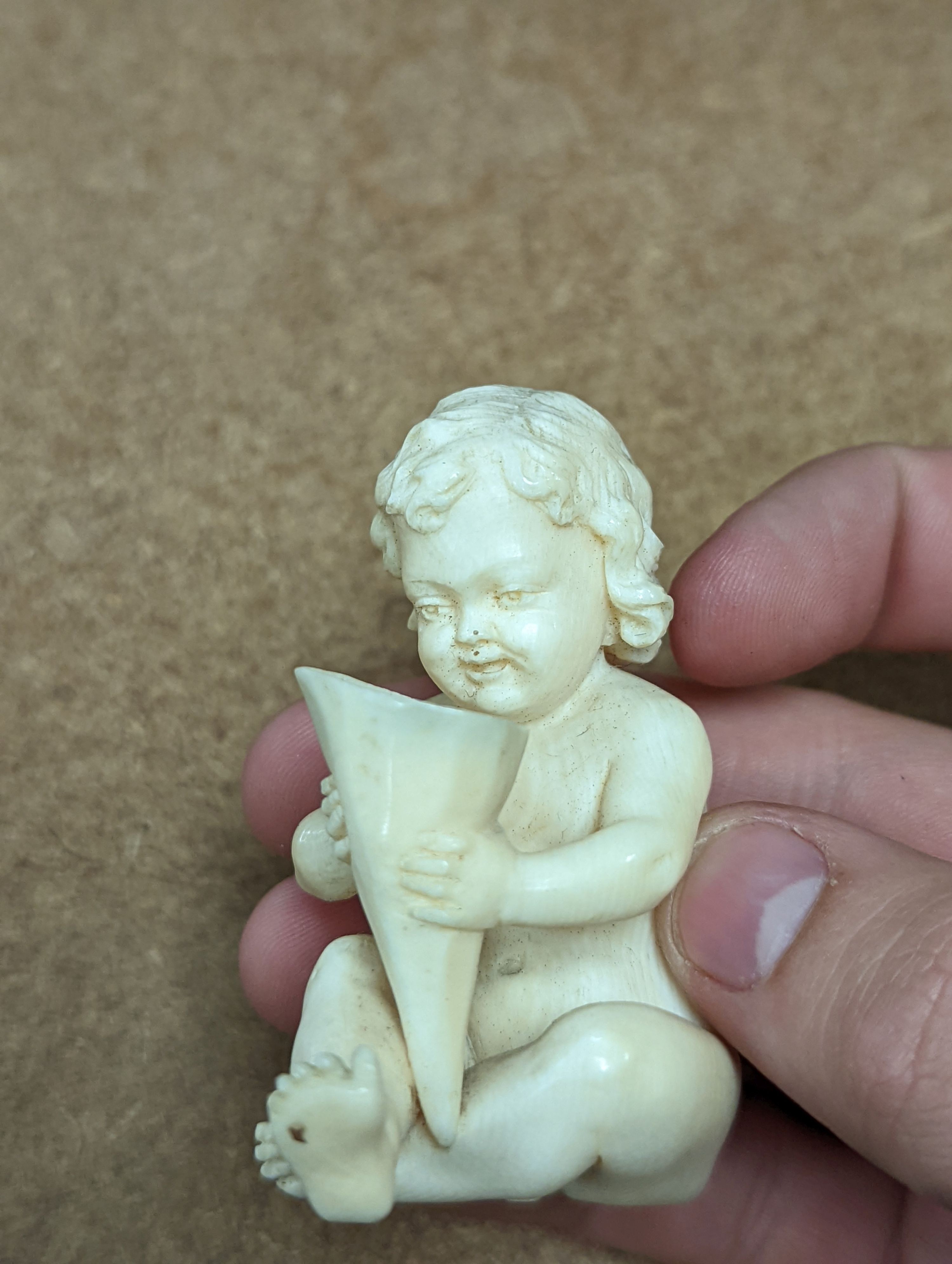 A 19th century Continental carved ivory figure of a child holding a cornucopia - 7cm tall